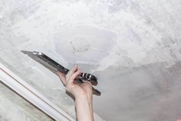 istock Hand with a putty knife and putty, apply mastic to the ceiling to level the surface 1377288699