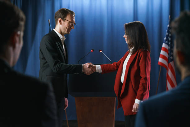 istock Two politicians shaking hands before debates, standing on a blue background with American flag 1377297741
