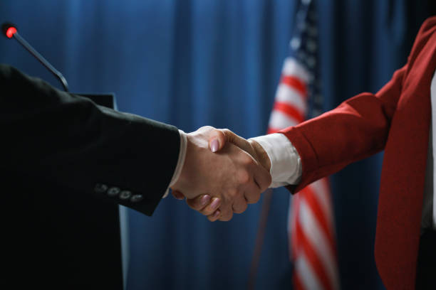 미국 국기와 파란색 배경에 협상 후 두 정치인의 악수의 클로즈업 - 의장 뉴스 사진 이미지