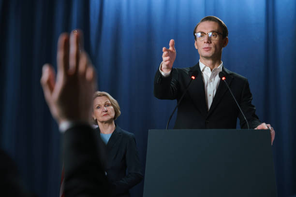 White young American politician listening to the questions after the debates White young American politician listening to the questions after the debates, standing behind the pedestal on a blue background president stock pictures, royalty-free photos & images