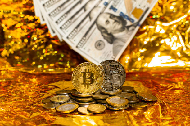 deux bitcoins sur une pile de pièces sur un fond de billets de cent dollars disposés dans un éventail sur fond doré - beak number 100 hundred dollar photos et images de collection