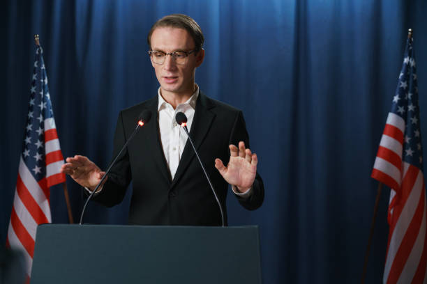 istock A young white politician pronouncing a speech,  standing against the blue background 1377312832