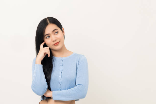 istock Beautiful asian woman thinking. Smiling female standing pose on isolated white background. Attractive Teenager girl around 25 looking at empty space for text feeling excited and thinking. 1377314128