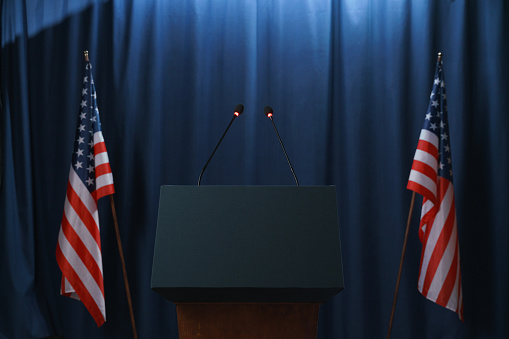 Escenario vacío antes o después de los debates con un pedestal y banderas estadounidenses de ambos lados photo