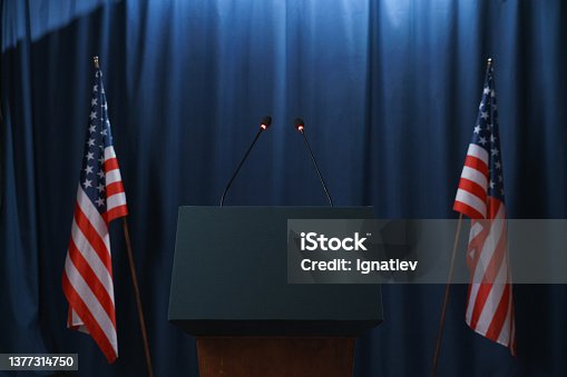 istock Empty stage before or after the debates with a pedestal and American flags from both sides 1377314750