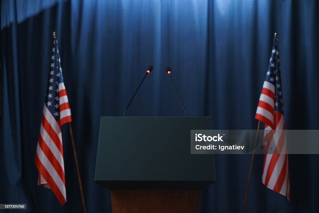 Empty stage before or after the debates with a pedestal and American flags from both sides Lectern Stock Photo