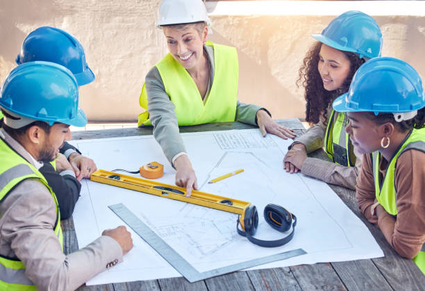 istock Cropped shot of a group of construction workers discussing blueprints while working on a building site 1377331578