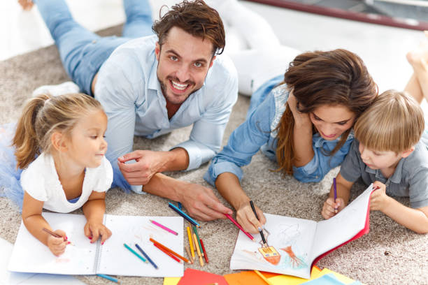 istock Young family coloring while relaxing on carpet at home. 1377336858