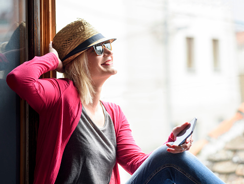 Young happy hipster woman with stylish hat, holding smartphone, laughing and enjoy the sun. Youth lifestyle concept.