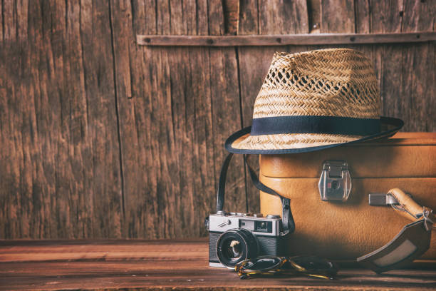 Vintage case, hipster hat, and retro camera on wooden background still life. Summer holiday vacation and adventure traveling concept with copyspace.