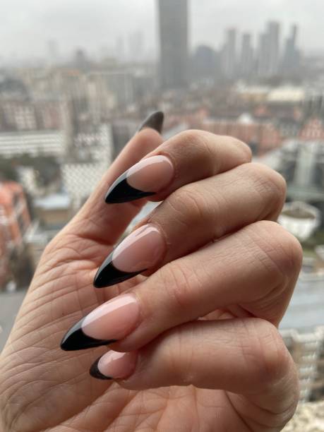 Black tip French manicure with claw points trendy nail design in acrylic applied nail art stock photo