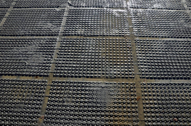 decal mat in muddy soil soaked in water. the compacted terrain does not absorb water and resembles a rice field with one repeating pattern with circles and rectangles, backdrop