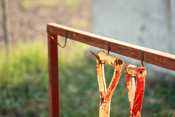 Part of shovels handle are hanging with hook on the metal rail for housekeeping and storage. Gardening working tool object photo.