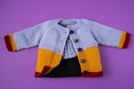 Knitted clothes color background. Handmade children's clothing. Knitted suit top view flat composition. The concept of hobby, individual marketing, entrepreneurship. Autumn time is cozy and warm.