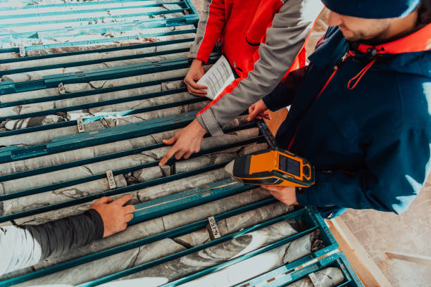 Geological gold core samples with team of mining workers measuring drilled rock top view. Selective focus