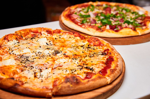 Pizza con salami, pimiento, tomates y queso, encurtidos, tocino y salchichas sobre un fondo ligero. Primer plano, enfoque selectivo photo