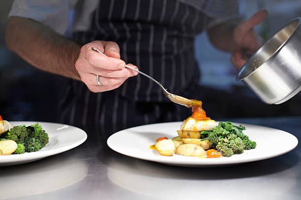 chef preparing dish in kitchen - bord serviesgoed fotos stockfoto's en -beelden