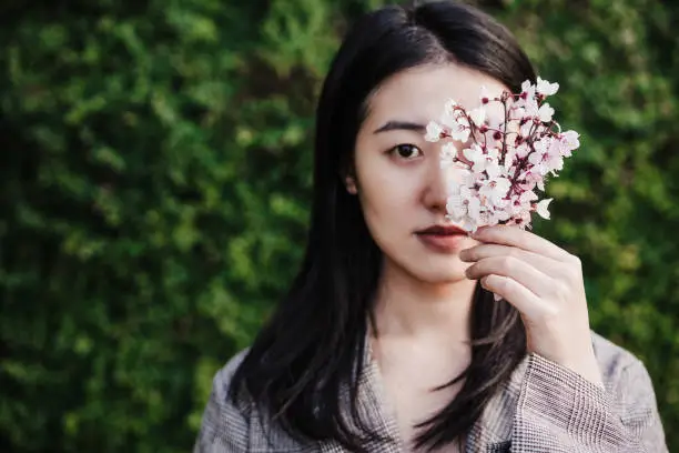 beautiful chinese asian woman holding almond tree flowers.Spring. selective focus on flowers