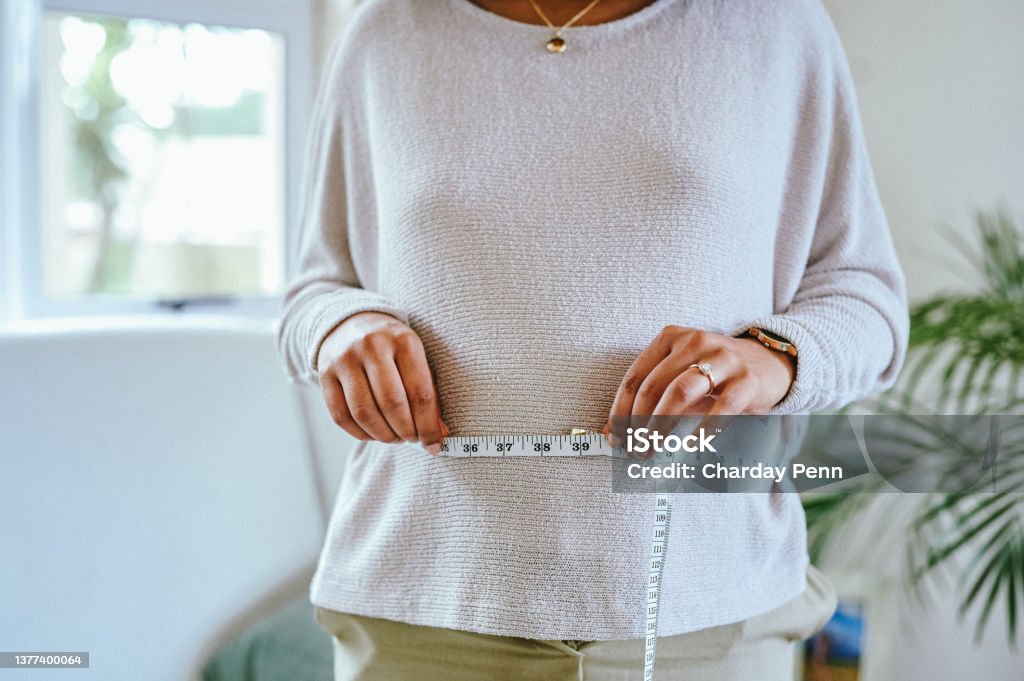 Shot of a pregnant woman measuring her belly at home Being pregnant is an occupational hazard of being a wife 20-24 Years Stock Photo