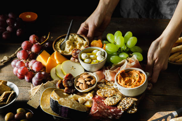 zbliżenie kobiety serwującej półmisek sera i mięsa - cheese platter zdjęcia i obrazy z banku zdjęć