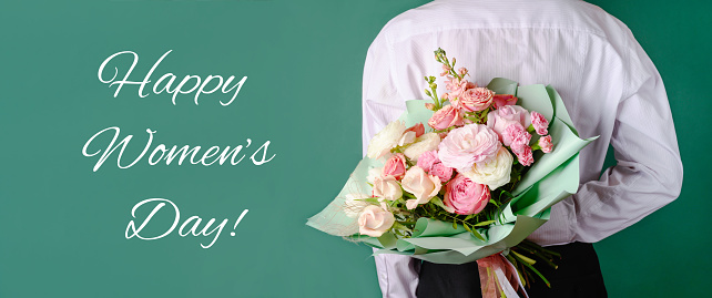 Man holding and giving a beautiful bouquet with flowers to woman on green background. Front view. Women's day, love concept. Copy space. Banner.
