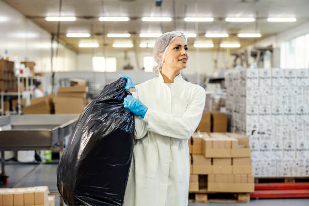 pracownica fabryki żywności nosi worek na śmieci podczas recyklingu. - garbage bag garbage bag food zdjęcia i obrazy z banku zdjęć