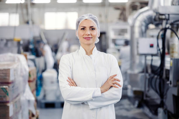 Portrait of successful food factory worker smiling at the camera. Portrait of a proud female food plant worker smiling at the camera. production line worker stock pictures, royalty-free photos & images