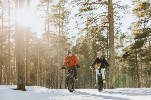 Father and daughter fatbiking in nature Senior father and adult daughter spending the day together, riding with fatbikes in nature. winter sport stock pictures, royalty-free photos & images