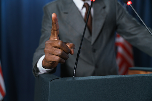 Close-up of a dark-skinned politician's hand pointing up during the speech, we don't  see a man, only his hand in the foreground