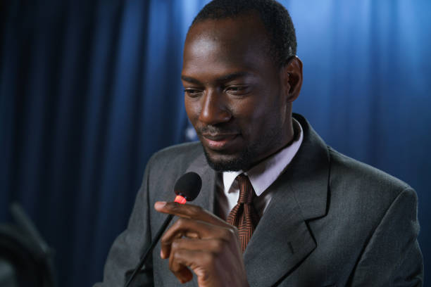 istock Smiling dark-skinned politician in a gray suit checking the microphone before the speech in close up 1377426290