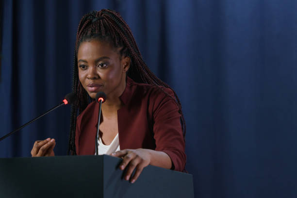 Young emotional American politician in close up against the dark blue curtain Young emotional American politician in close up against the dark blue curtain woman press conference stock pictures, royalty-free photos & images