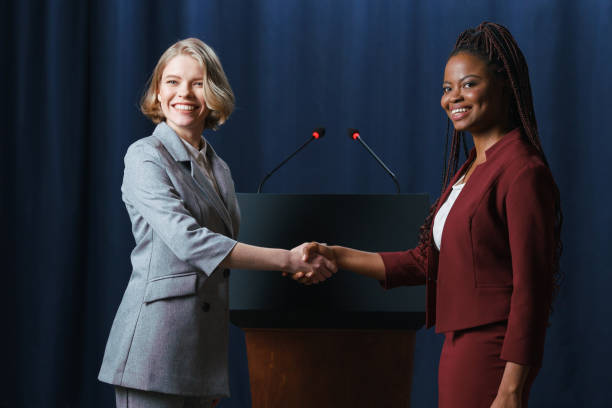 istock Young beautiful female politicians shaking hands on camera with smiles 1377434597