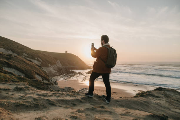 istock Man taking a photo of a beautiful beach landscape 1377435121