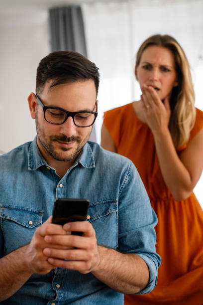 young couple with smartphone having quarell and marriage conflict because of cheating - quarell imagens e fotografias de stock