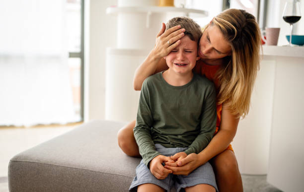 Portrait of mother consoling her crying sad injured son. Child family support parent concept stock photo