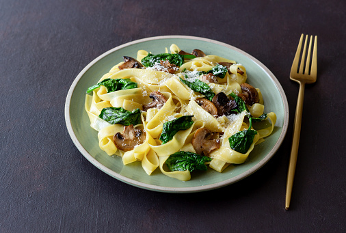 Linguini pasta with mushrooms, spinach and cheese. Healthy eating. Vegetarian food. Italian cuisine