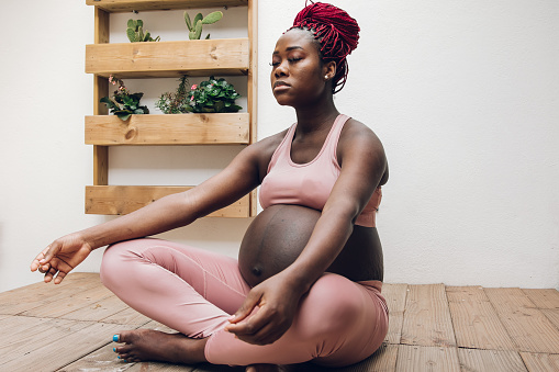 Black pregnant woman doing some ioga and meditation