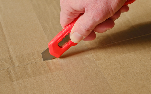 Opening a cardboard box with a utility knife.
