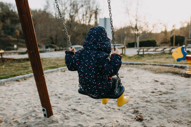 istock Rear View Of Girl Sitting On Swing 1377493932