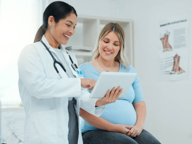 shot of a doctor during a consultation with a pregnant patient in a clinic - prenatal care imagens e fotografias de stock