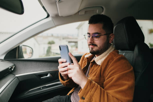 Young man inside car using a smart phone stock photo