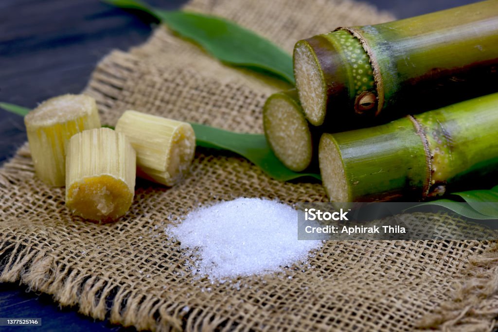 Corte a parte do bastão de açúcar e o açúcar branco na opinião superior de madeira do fundo - Foto de stock de Açúcar royalty-free