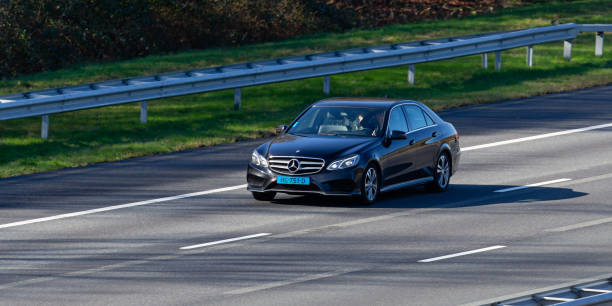 Rijssen, Overijssel, Netherlands, february 23rd 2022, Dutch black 2015 Mercedes 4th generation E-class 220D (220 BlueTEC) taxi approaching on the Dutch A1 highway at Rijssen - the E-class is a line of executive cars made by German, Stuttgart based car manufacturer Mercedes-Benz since 1993\n\nThe A1 is a 157 km long highway that crosses the country from West (Amsterdam) to East (Germany)