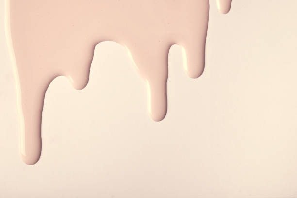 istock Light brown liquid drops of paint color flow down on beige background. Abstract cream backdrop with fluid drip pattern 1377533802