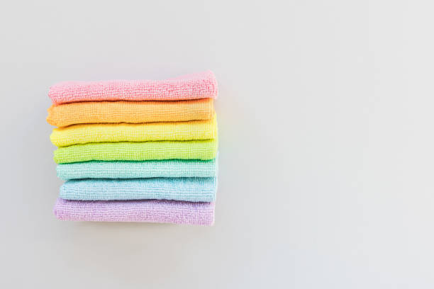 New folded microfiber cloth for cleaning in seven rainbow colors on gray background. Cleaning micro fabric towels for dusting and polishing. Domestic household cleaning service concept. Top view, copy space