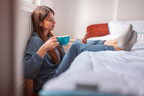istock Woman using smart phone, drinking coffee and relaxing at home 1377555131