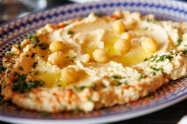 Close-up on hummus with olive oil and chick-pea on top, garnished with paprika and parsley, served in ornated plate, Middle Eastern cuisine fine dining