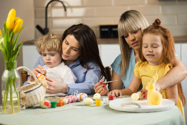 istock Two mothers with their children paint Easter eggs in the kitchen 1377585006
