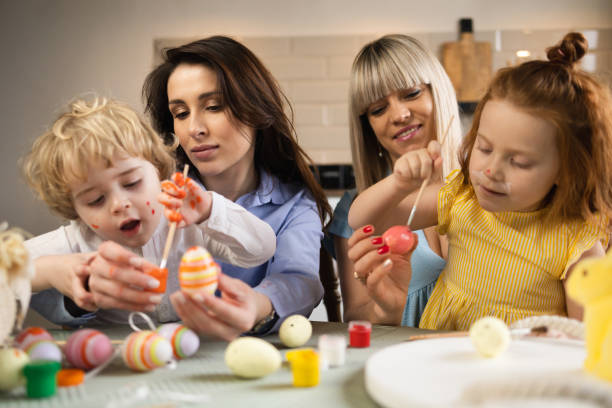istock Two mothers with their children color eggs in preparation for Easter 1377585643
