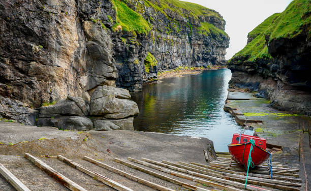 Wooden boat in Natural harbor of Gjodv village. Eysturoy island. Atlantic ocean, Faroe Islands, Kingdom of Denmark, Europe. Wooden boat in Natural harbor of Gjodv village. Eysturoy island. Atlantic ocean, Faroe Islands, Kingdom of Denmark, Europe. eysturoy stock pictures, royalty-free photos & images